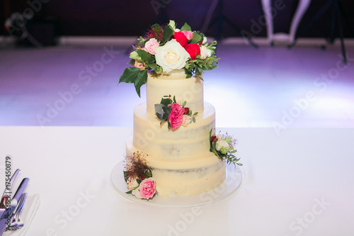 White wedding cake with flowers on table in restaurant