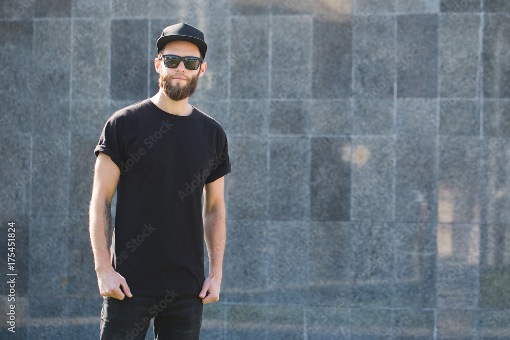 Hipster handsome male model with beard wearing black blank t-shirt with space for your logo or design in casual urban style Hipster handsome male model with beard wearing black blank t-shirt with space for your logo or design in casual urban style