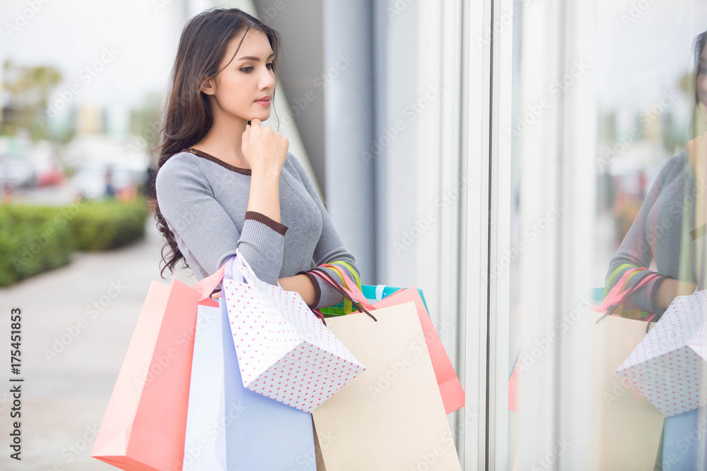 happiness, consumerism, sale and people concept - smiling young Asia woman with shopping bags at outdoor shopping mall happiness, consumerism, sale and people concept - smiling young Asia woman with shopping bags at outdoor shopping mall