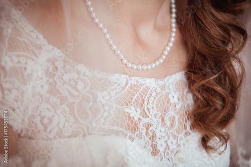 beautiful guipure on a dress of the bride. Pearl necklace on