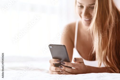 Close up of a smartphone in hands of a beautiful smiling woman