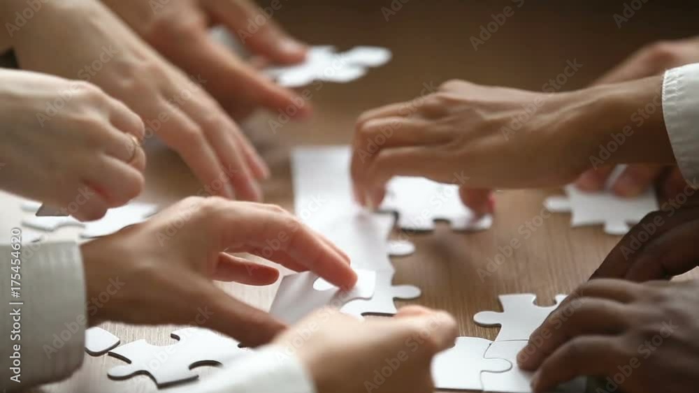 Close up view of hands assembling jigsaw puzzle on table, group of business people matching pieces playing board game, right decision making in business, help and support in teamwork concept Close up view of hands assembling jigsaw puzzle on table, group of business people matching pieces playing board game, right decision making in business, help and support in teamwork concept