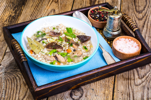 Fotografija Vegetarian soup with mushrooms and pearl barley for lunch on wooden table