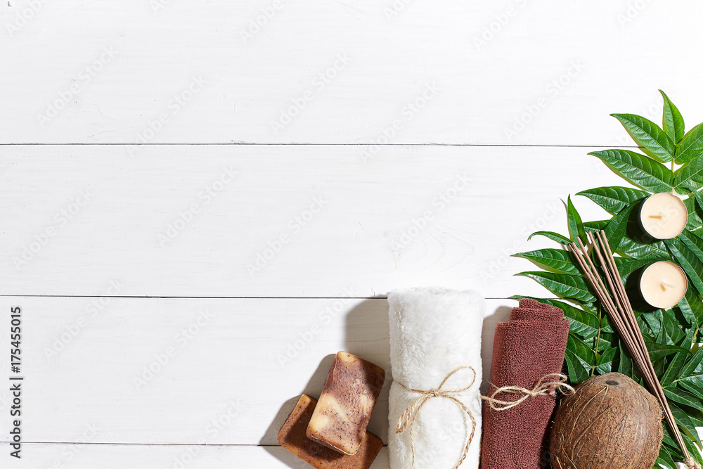 Spa set with towel and soap on white wooden background with green leaves Spa set with towel and soap on white wooden background with green leaves