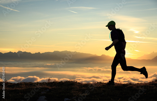 Athlete trailrunning in the mountains during a nice sunrise.