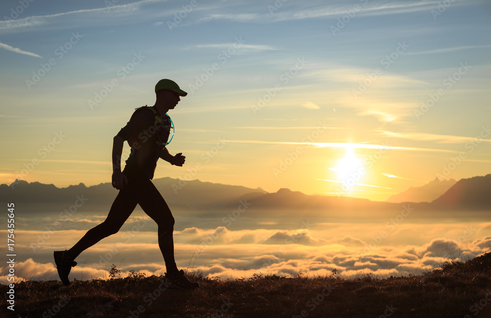 Athlete trailrunning in the mountains during a nice sunrise.