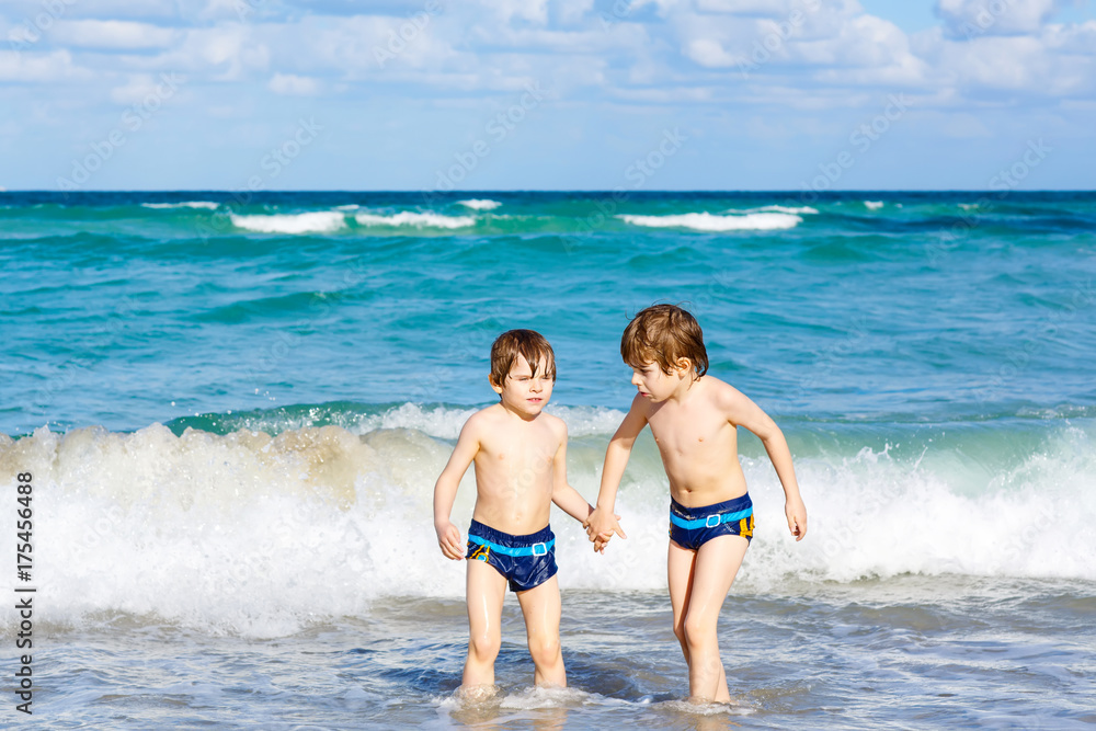 Two kid boys running on ocean beach in Florida