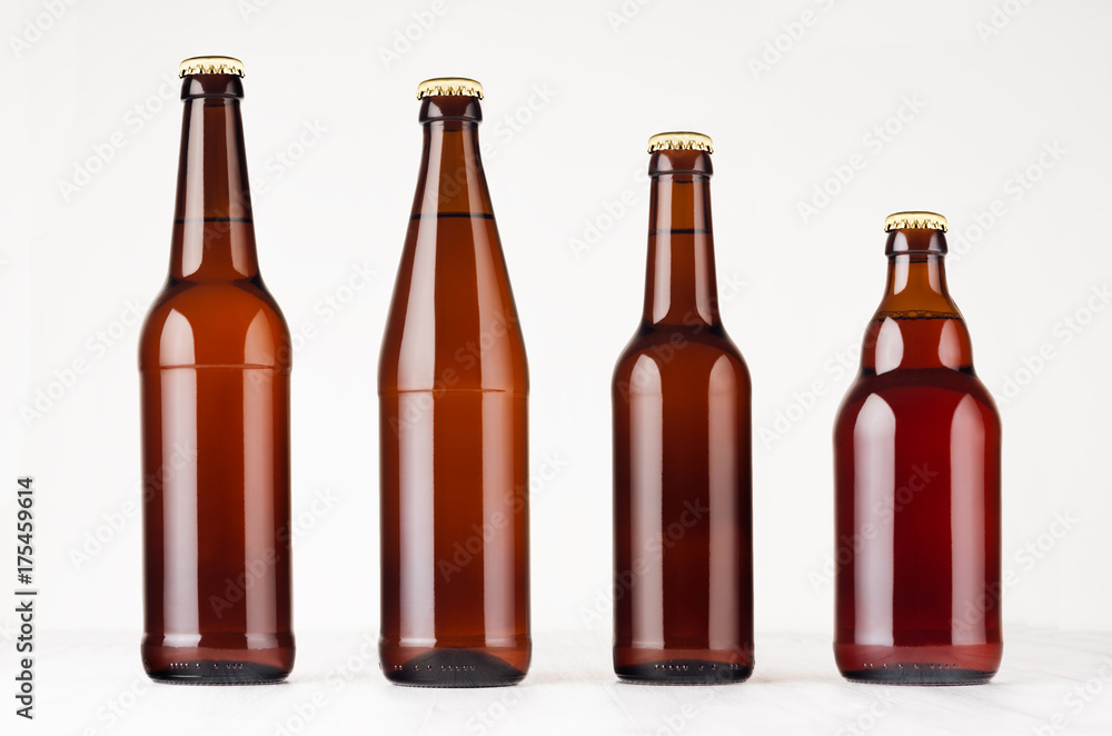 Collection different brown beer bottles, mockup. Template for advertising, design, branding identity on white wood table. Collection different brown beer bottles, mockup. Template for advertising, design, branding identity on white wood table.
