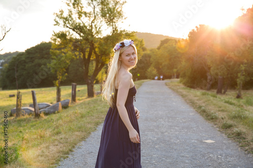 Woman on rural road wearing strapless dress looking over shoulder at camera smiling