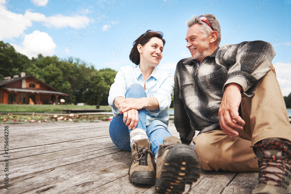 Mature couple relaxing on wooden decking, smiling