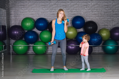 Mother and baby girl do exercises together in the gym