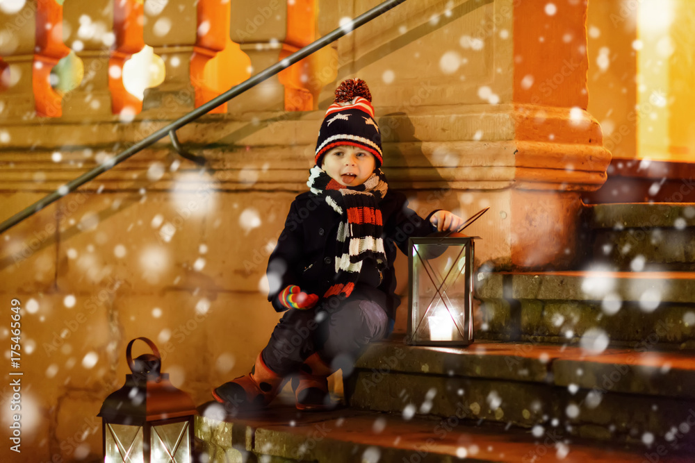 Little cute kid boy with with a light lantern on stairs near church. Little cute kid boy with with a light lantern on stairs near church.