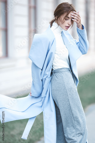 young beautiful stylish woman walking in street in blue coat, autumn fashion trend, smiling, happy.