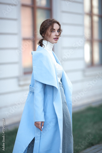 young beautiful stylish woman walking in street in blue coat, autumn fashion trend, smiling, happy.