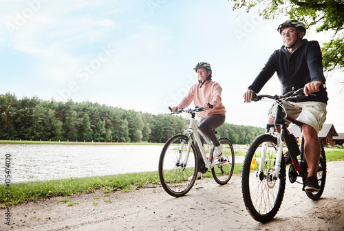 Mature couple cycling beside lake photo