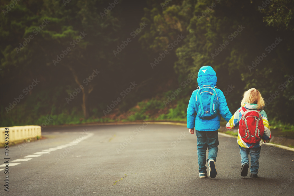 Obraz premium kids go to school - brother and sister walk on the road