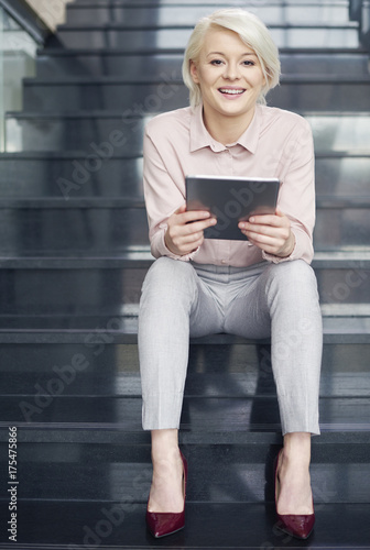Businesswoman with digital tablet sitting on stairs