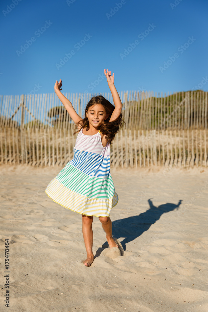 Little girl twirling and dancing on a sandy beach Little girl twirling and dancing on a sandy beach