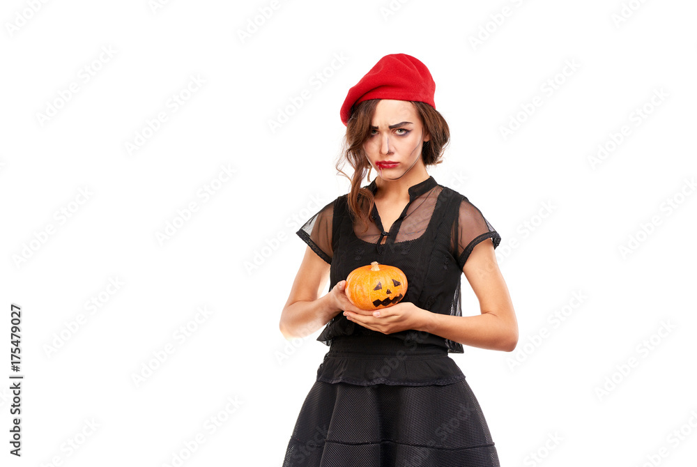 Studio portrait of young woman in Halloween costume posing with jack-o-lantern Studio portrait of young woman in Halloween costume posing with jack-o-lantern