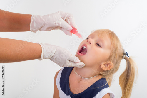 Canvas Print little girl on reception at the doctor receives the polio vaccine, a child being