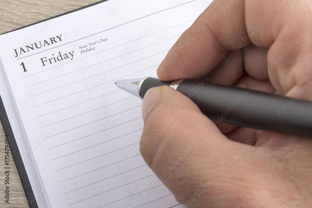 Man's hand holds a metal pen ready to set goals for the new year Man's hand holds a metal pen ready to set goals for the new year