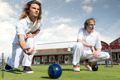 Two young men lawn bowling on bowling green