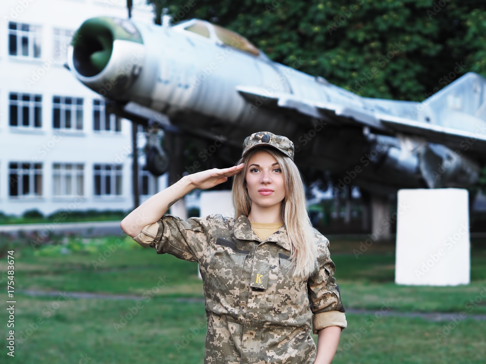 Blonde girl in military uniform staying near the plane looking at camera Blonde girl in military uniform staying near the plane looking at camera