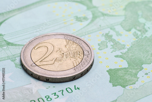 Coin two euros on the banknote of one hundred euro