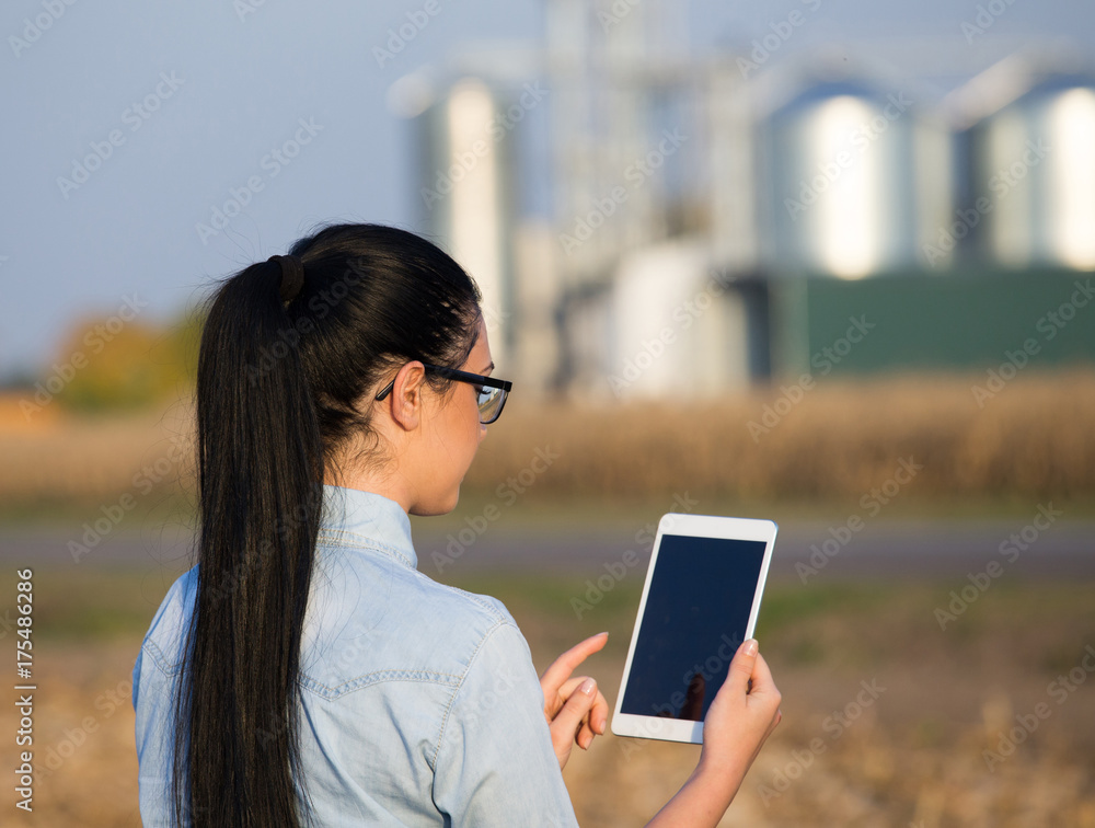 Fototapeta premium Farmer woman with tablet and silos