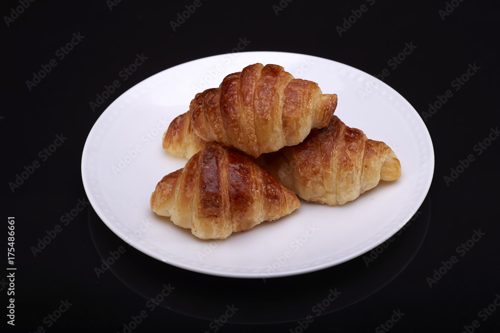 Tasty croissants with plate on black backgound Tasty croissants with plate on black backgound