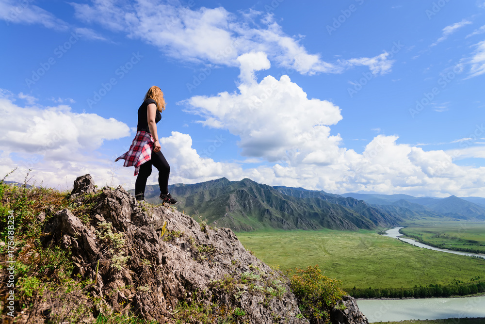 Obraz premium Woman stands on edge of cliff and looking at sun valley and mountains