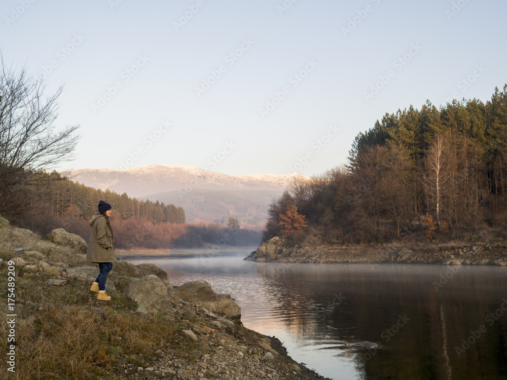 Solitary young woman standing by a lake