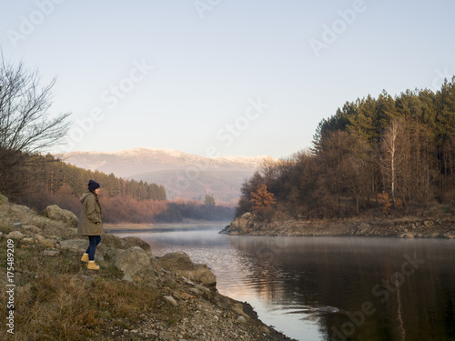 Solitary young woman standing by a lake © mastock