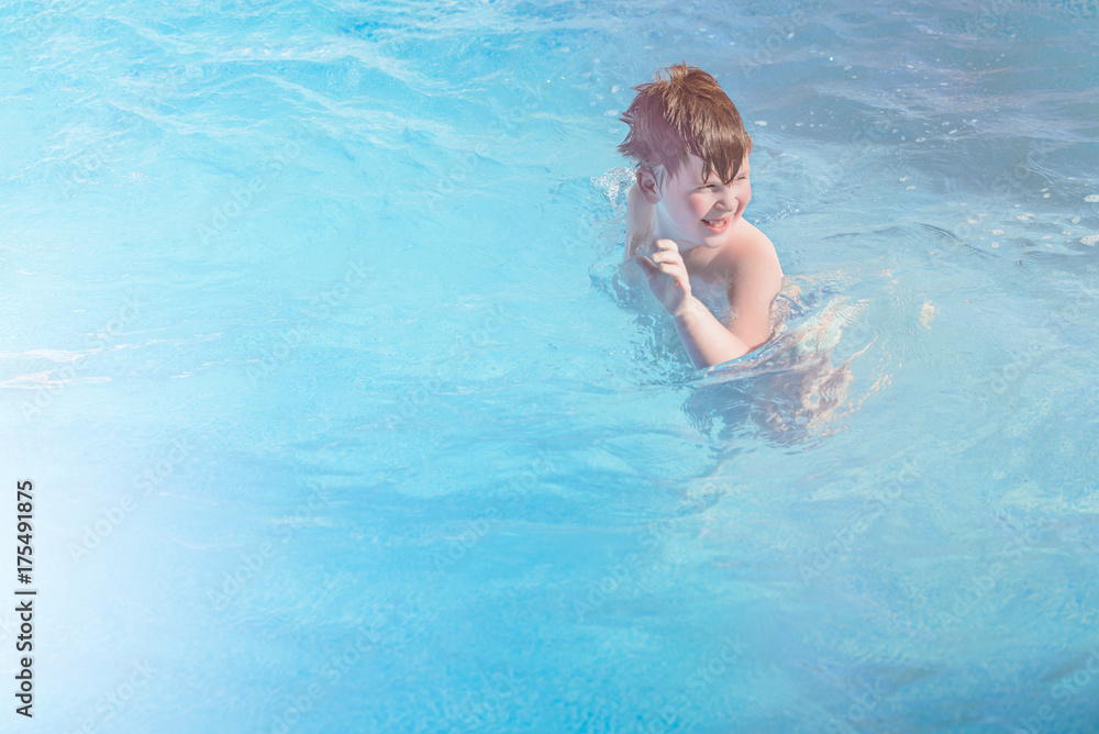 Happy little boy is swimming in the pool