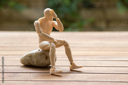 Man sitting on the stone, keeping his hand on the head
