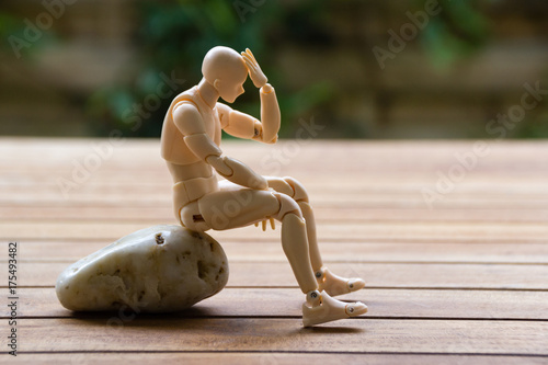 Man sitting on the stone, keeping his hand on the head photo