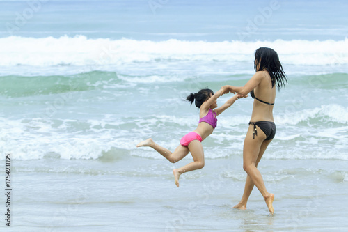 Happiness mother and daaughter in swimingsuit playing together on the beach family healthy travel concept
