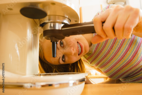 Woman in kitchen making coffee from machine