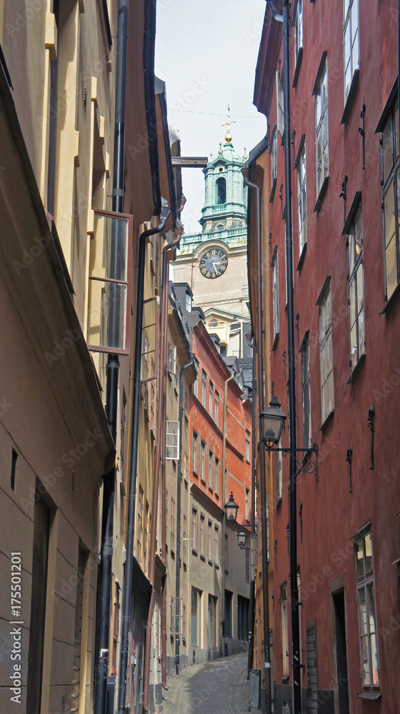 Narrow colorful street in Gamla Stan and tower of the church St. Nicholas (Storkyrkan), sunny day, Stockholm, Sweden