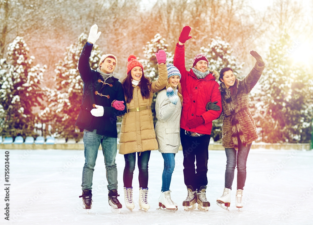 Obraz premium happy friends ice skating on rink outdoors
