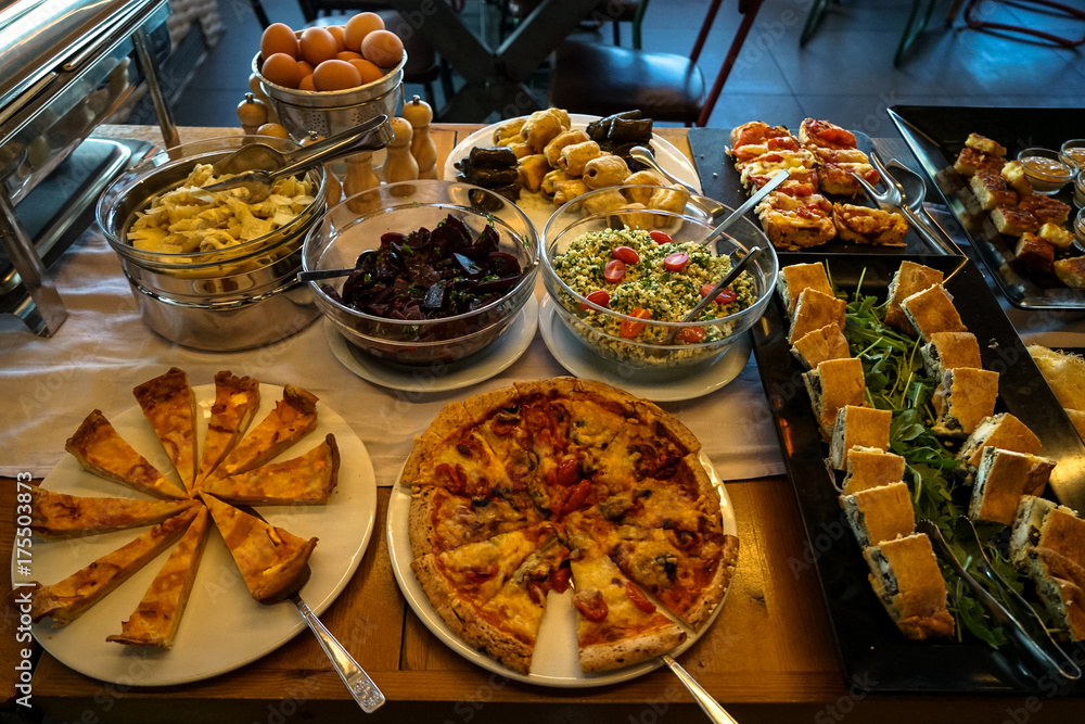 Greek breakfast buffet table full with varieties of pizza, pies, pasta,  beetroot, couscous salads, boiled eggs, local dishes, etc. Stock Photo |  Adobe Stock