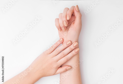 Closeup of hands of a young woman with manicure on nails against white background 