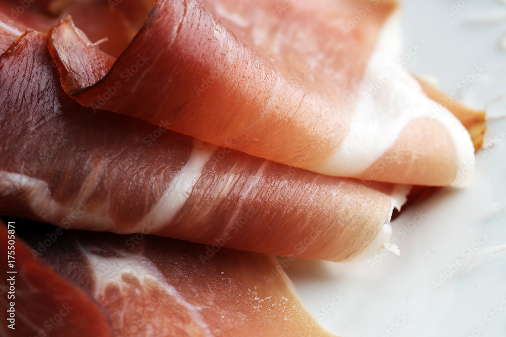 Fototapeta premium Italian prosciutto crudo or jamon. Raw ham on white dish.