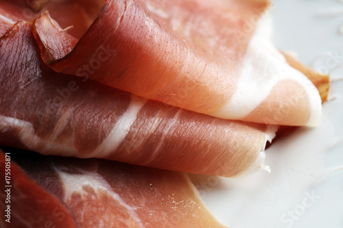 Italian prosciutto crudo or jamon. Raw ham on white dish.