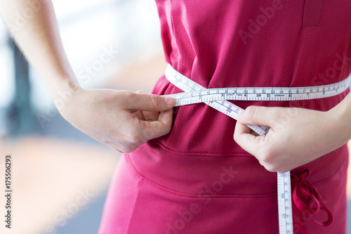 Close up Sport woman measuring her waist by using waistline, comparing her waist size before and after workout for firming body - Healthcare concept