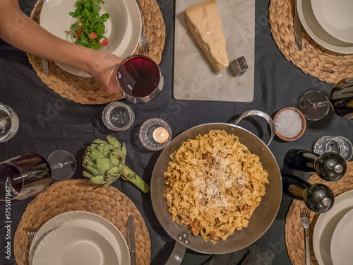 Top view of dinner table. Pasta with parmesan cheese. Hand holdning glass of red wine. photo