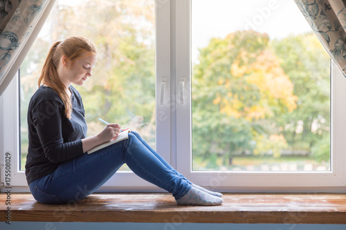 Girl sitting at the window and planning her life with notes Free Download Girl sitting at the window and planning her life with notes - GFXLoad