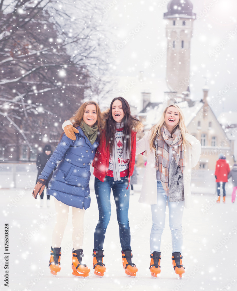 Beautiful skating girls. Open air rink at winter. Falling snow. Christmas concept.