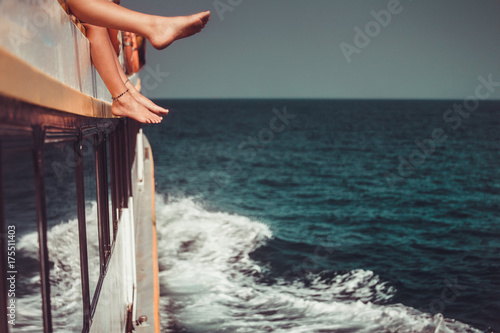 Young people chilling in catamaran boat - Relaxed people making tour ocean trip - Travel, summer, friendship, tropical concept. Only legs close up. Retro vintage toning effect photo