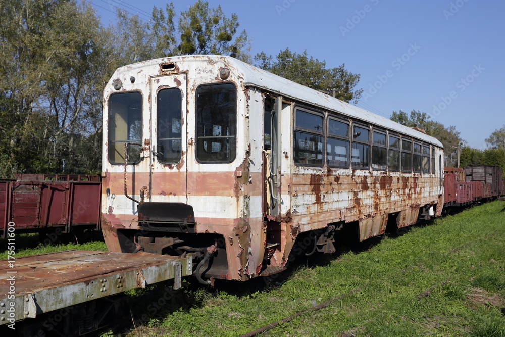Old ruined steel passenger car. Rusty train on railway tracks.
